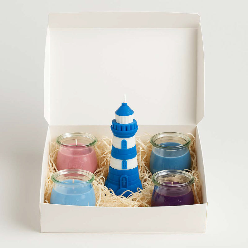 Geschenkset Küstenzauber: weiße Box mit 4 maritimen Mini-Duftkerzen im WECK-Glas und einer blauen Leuchtturm-Kerze aus Rapswachs, dekoriert mit Curly-Füllun
