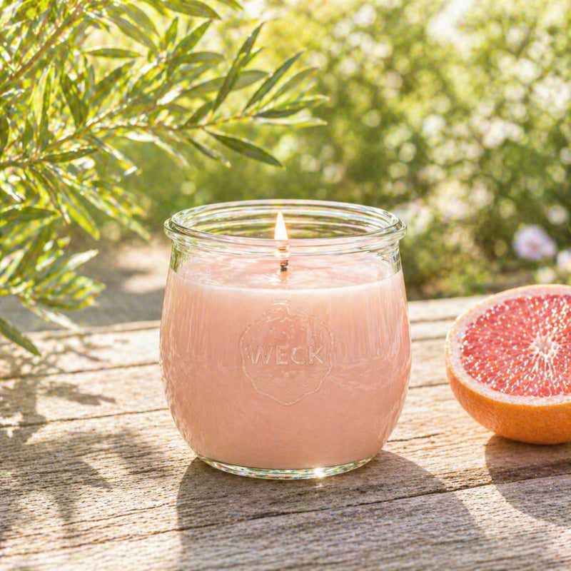 Grapefruit Duftkerze im WECK-Glas im Garten auf Holztisch bei natürlichem Sonnenlicht
