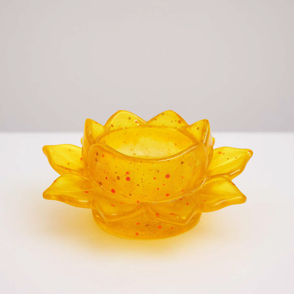Handgefertigter Kerzenhalter in Lotosblumenform aus gelben Epoxidharz mit Glitzereffekten – auf weißem Hintergrund fotografiert.