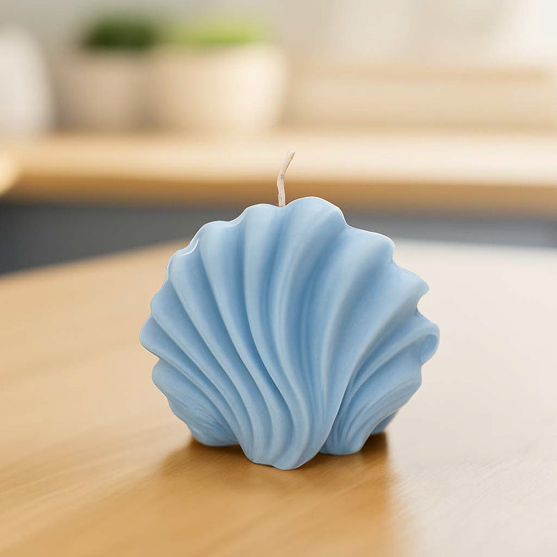 Dekorative Muschelkerze aus Rapswachs in zartem Blau auf einem Holzuntergrund – stimmungsvolle Sommerdeko