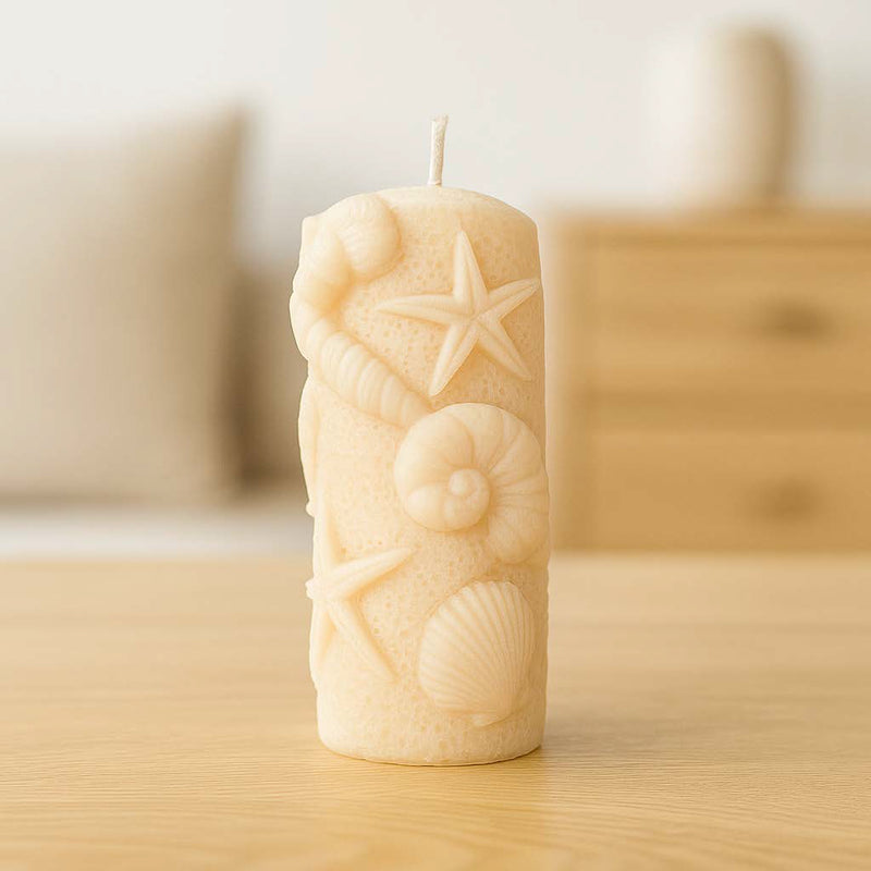 Handgemachte Stumpenkerze aus Rapswachs mit eingeprägten Muscheln und Seesternen – dekorativ inszeniert auf hellem Untergrund mit maritimer Stimmung.