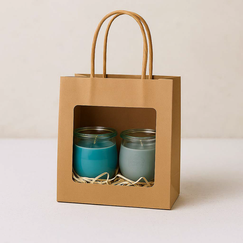 Zwei Mini-Duftkerzen in einer Kraftpapiertüte mit Sichtfenster – Sorten Nordische Küste & Klarer Horizont, maritim verpackt mit Holzwolle.