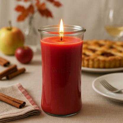 Brennende Apfel-Zimt XXL-Duftkerze auf gedecktem Wintertisch mit Äpfeln, Zimtstangen und Tannenzweigen in stimmungsvoller Wohnatmosphäre