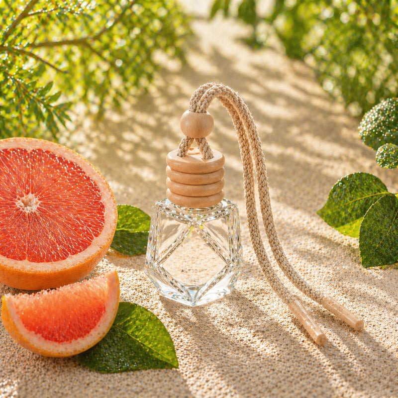 Grapefruit Autoduft in Glasflasche auf hellem Stein mit frischer Grapefruit im Sonnenlicht