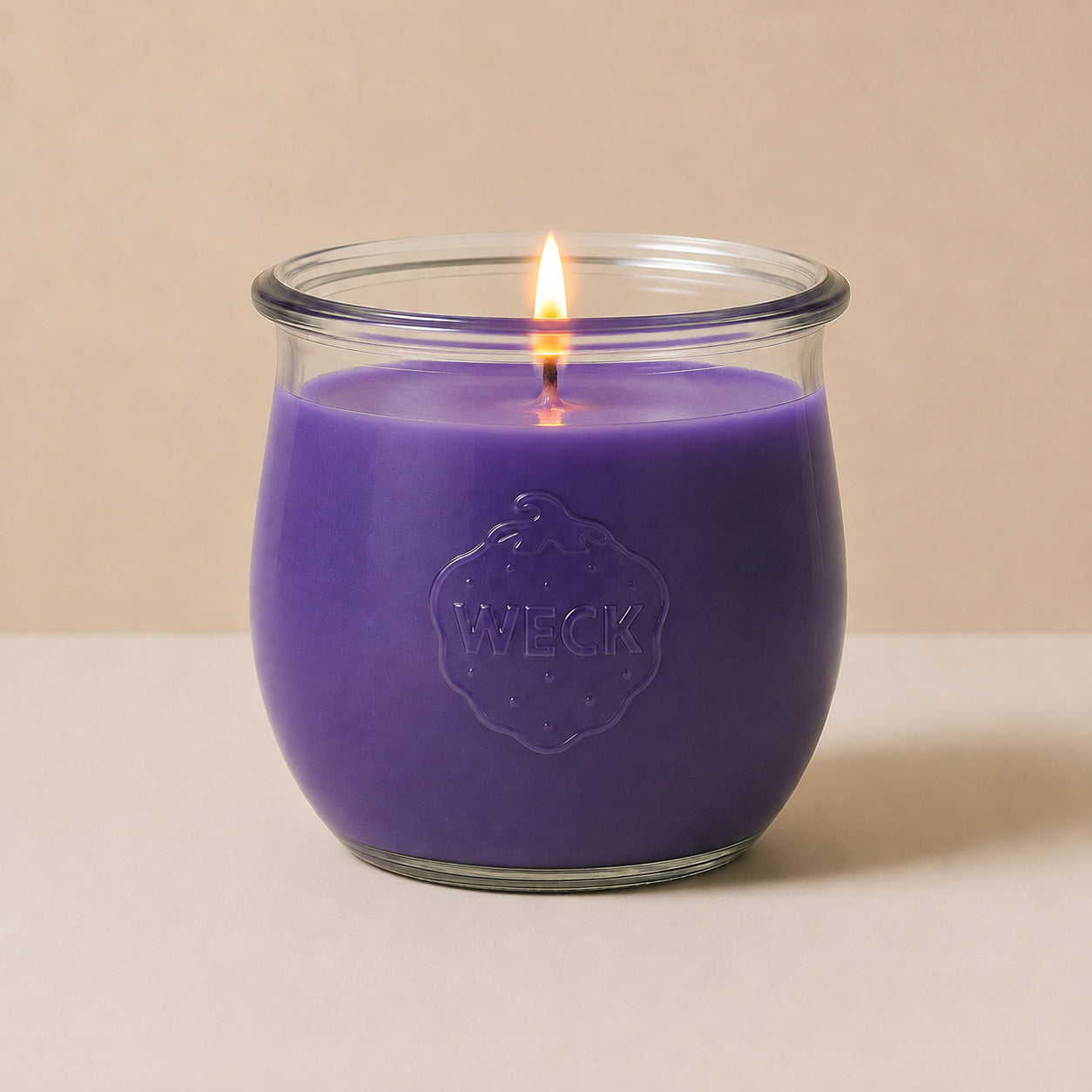 Lila große Duftkerze aus Kokoswachs im WECK-Tulpenglas von CandleDeko, brennend vor neutralem Hintergrund.