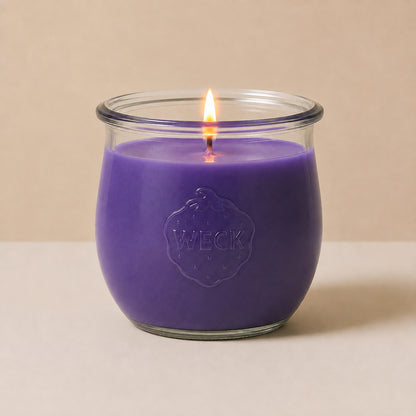 Lila große Duftkerze aus Kokoswachs im WECK-Tulpenglas von CandleDeko, brennend vor neutralem Hintergrund.
