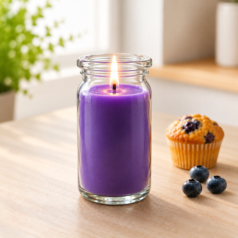 Blaubeer-Muffin kleine Duftkerze aus Kokoswachs im WECK-Glas von CandleDeko, lila und brennend neben einem Blaubeermuffin auf Holztisch.