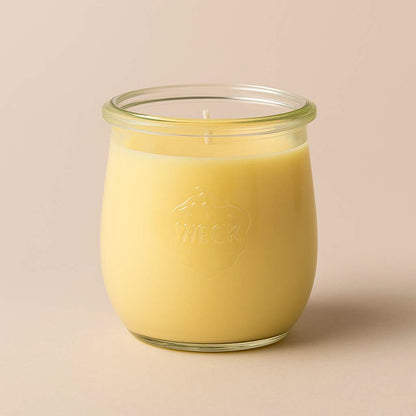 Gelbe Duftkerze „Frische Ananas“ im kleinen WECK-Tulpenglas, mit glatter Oberfläche, vor warm-beigem Hintergrund.