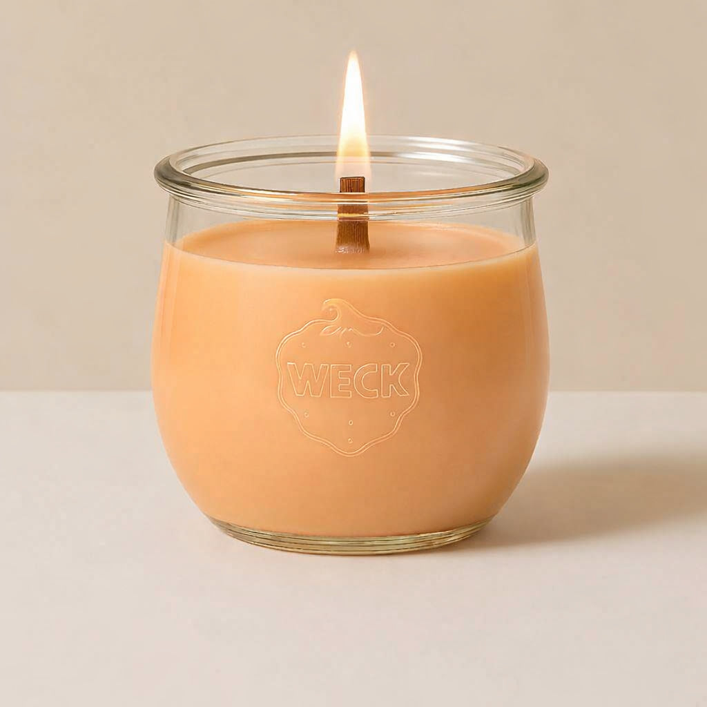 Guava Colada Duftkerze im WECK-Glas mit apricotfarbenem Wachs und brennendem Holzdocht vor hellem Hintergrund