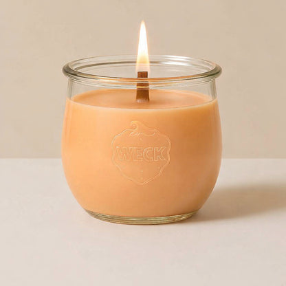 Guava Colada Duftkerze im WECK-Glas mit apricotfarbenem Wachs und brennendem Holzdocht vor hellem Hintergrund