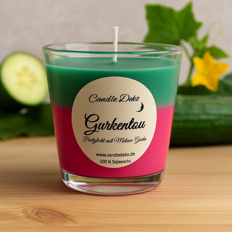 Zweifarbige Duftkerze im Glas mit oberer grüner und unterer pinker Farbschicht. Etikett mit der Aufschrift "Gurkentau – Partylicht mit Melone-Gurke".