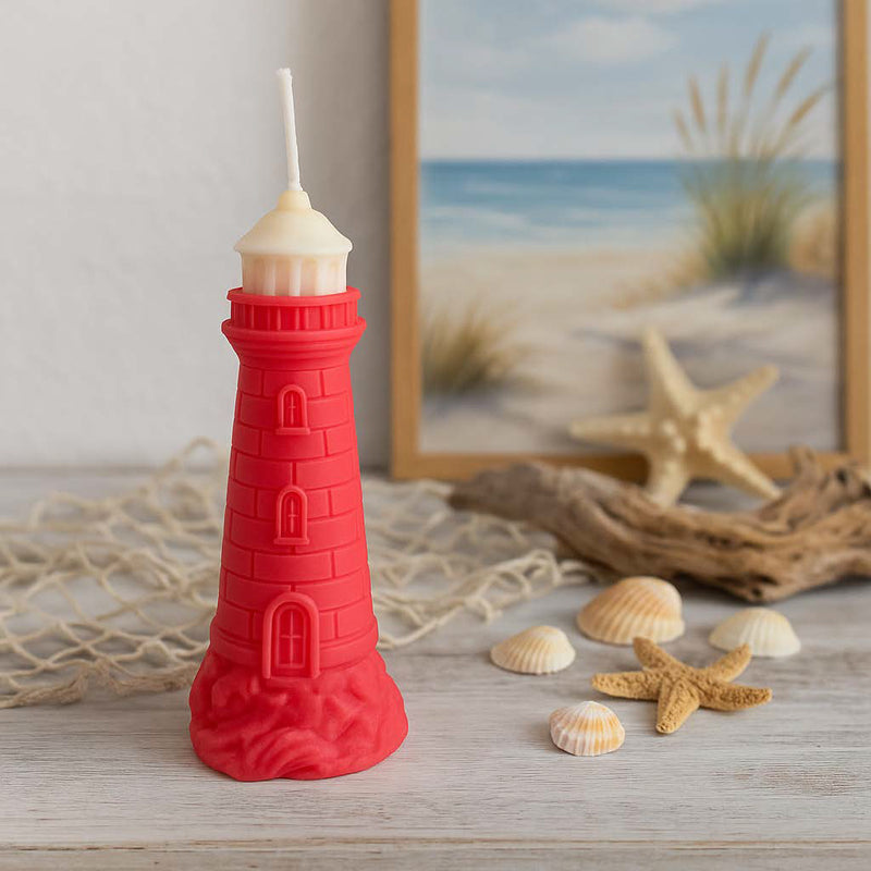 Rote Leuchtturm-Kerze aus Rapswachs, brennend in maritimer Dekoszene mit Muscheln, Seestern und Treibholz