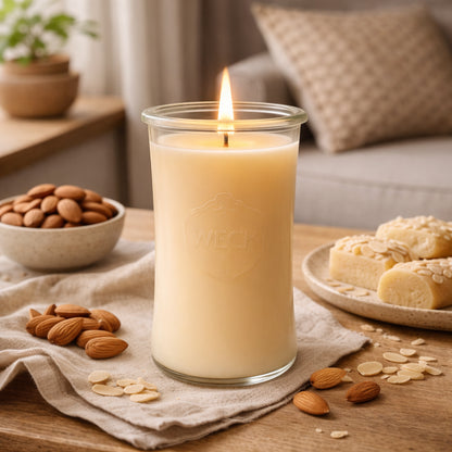 Große Duftkerze Marzimandel im hohen WECK-Glas mit cremegelbem Wachs und brennendem Holzdocht, vor warmem beigefarbenem Hintergrund.