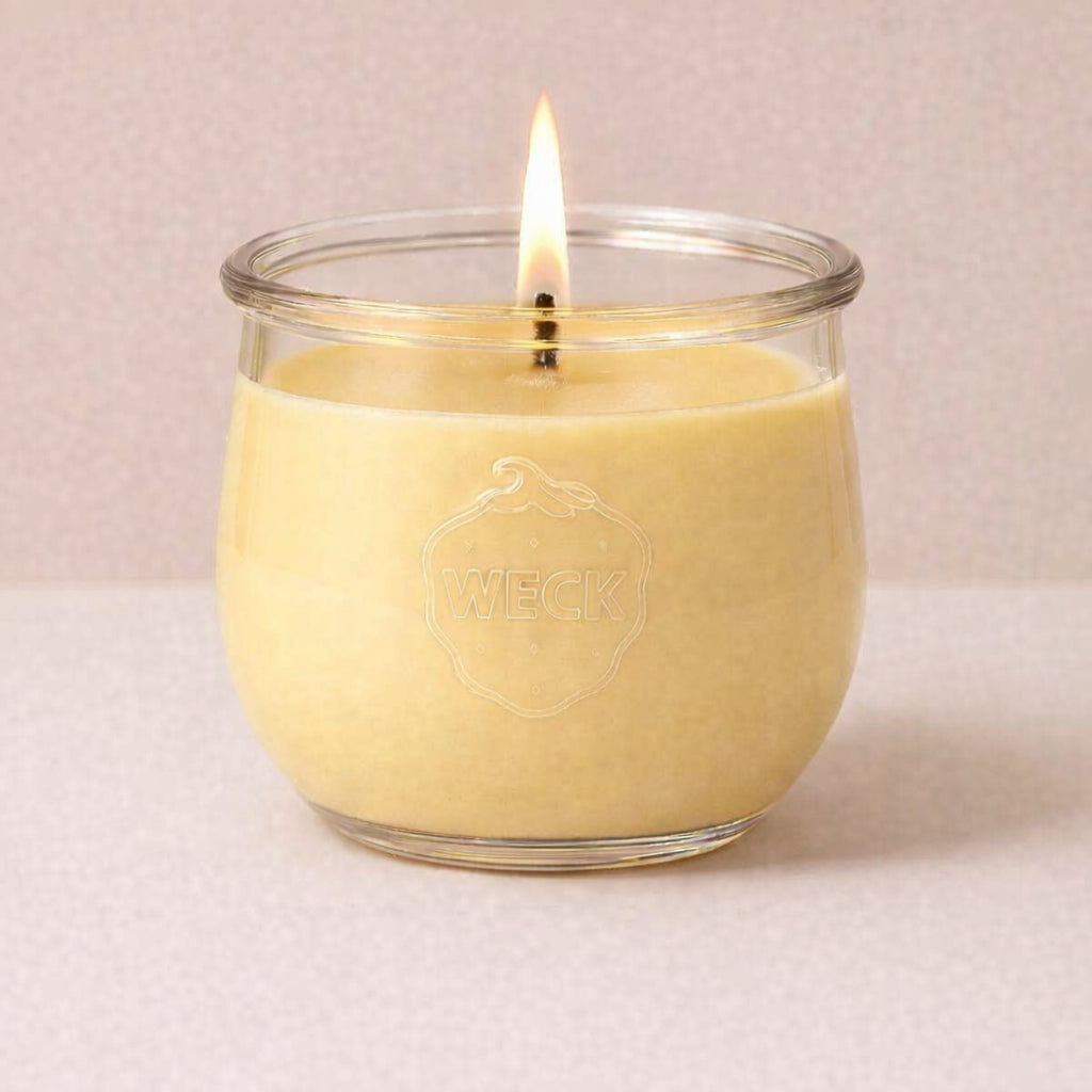 Lila Duftkerze im WECK-Glas mit Holzdocht vor neutral beigem Hintergrund, unangezündet.