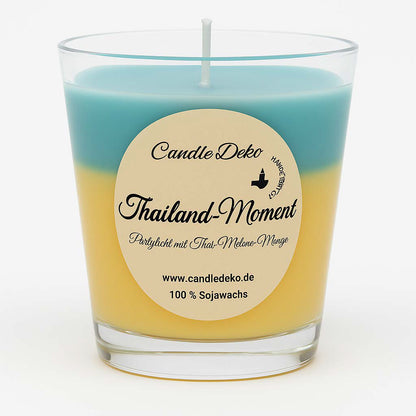 Duftkerze im Glas mit zwei Farbverläufen: oben mintgrün, unten mango-gelb. Auf dem Etikett steht "Thailand-Moment – Partylicht mit Thai-Melone-Mango".