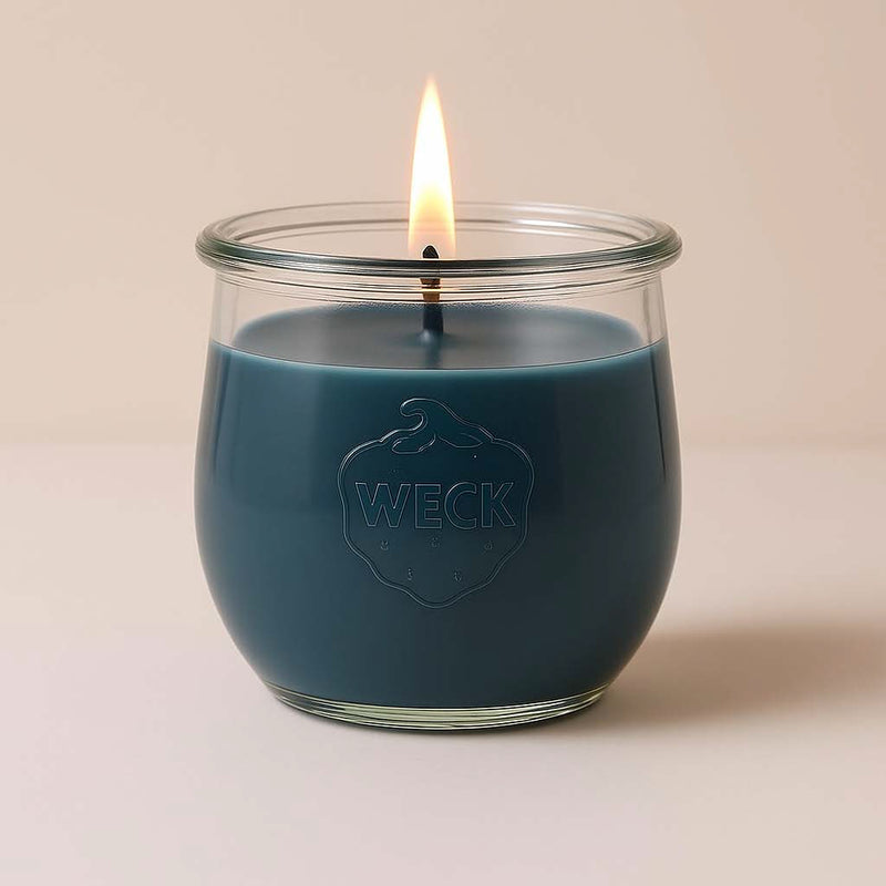Graublaue Duftkerze Windstille im WECK-Glas, klassisches Design mit Baumwoll-Docht, brennend mit warmer Flamme vor neutralem Hintergrund