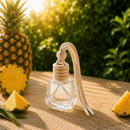CandleDeko Ananas Autoduft Flakon auf Steintisch neben einer frischen Ananas im warmen Sonnenlicht.