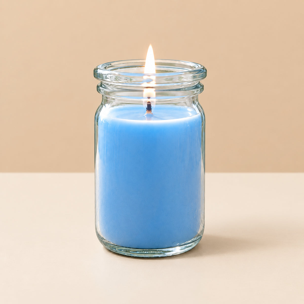 blaue kleine brennende Duftkerze von Candledeko vor neutralem Hintergrund