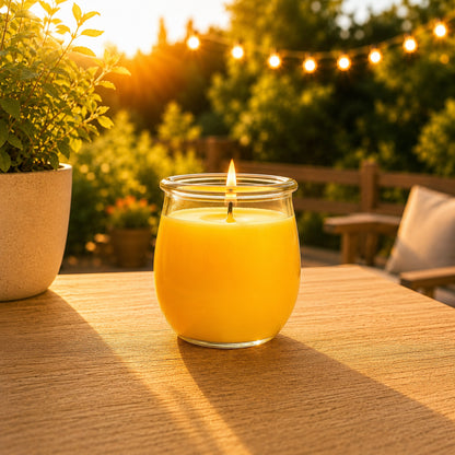 Große Citronella Duftkerze aus Kokoswachs im WECK-Tulpenglas auf Holztisch vor leuchtender Lichterkette bei Sonnenuntergang.