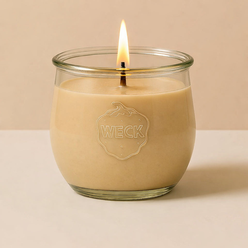Brennende beige CandleDeko grosse Duftkerze im WECK-Tulpenglas vor neutralem Hintergrund.