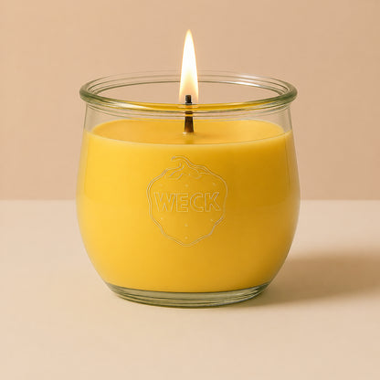 Brennende gelbe CandleDeko grosse Duftkerze im WECK-Tulpenglas vor neutralem Hintergrund.
