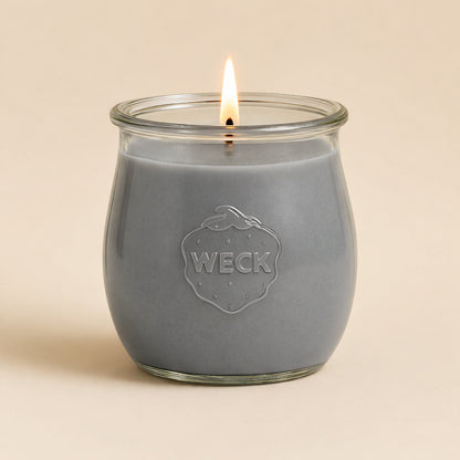 Brennende graue CandleDeko grosse Duftkerze im WECK-Tulpenglas vor neutralem Hintergrund.