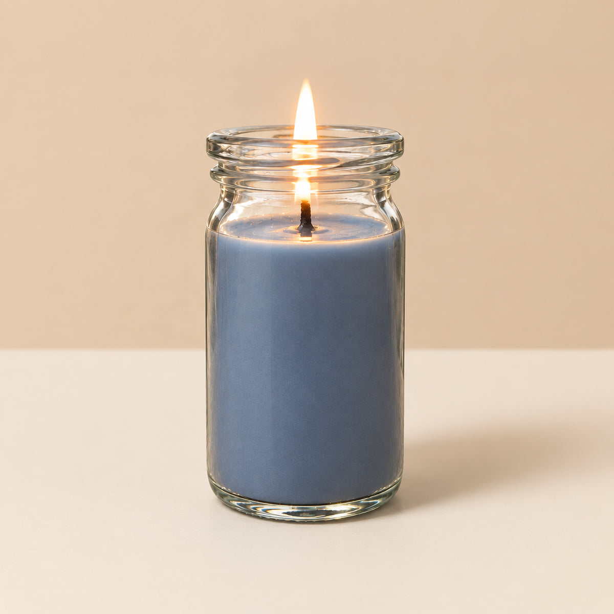 Graublaue kleinee Duftkerze aus Kokoswachs im WECK-Glas von CandleDeko, brennend vor neutralem Hintergrund.