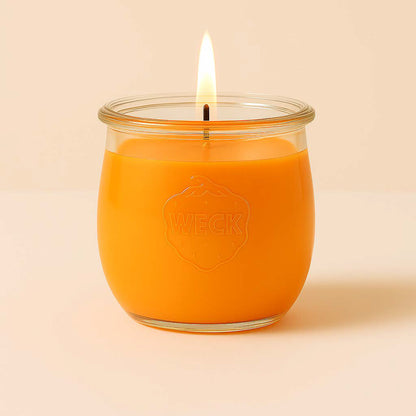 Brennende orange CandleDeko grosse Duftkerze im WECK-Tulpenglas vor neutralem Hintergrund.