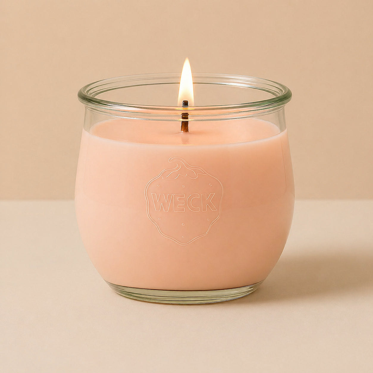Brennende pfirsichfarbene CandleDeko grosse Duftkerze im WECK-Tulpenglas vor neutralem Hintergrund.