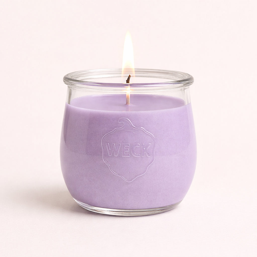 Brennende lila CandleDeko große Duftkerze im originalen bauchigen WECK-Glas vor neutralem Hintergrund