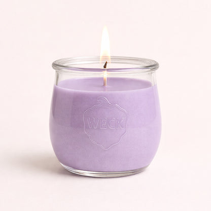 Brennende lila CandleDeko große Duftkerze im originalen bauchigen WECK-Glas vor neutralem Hintergrund