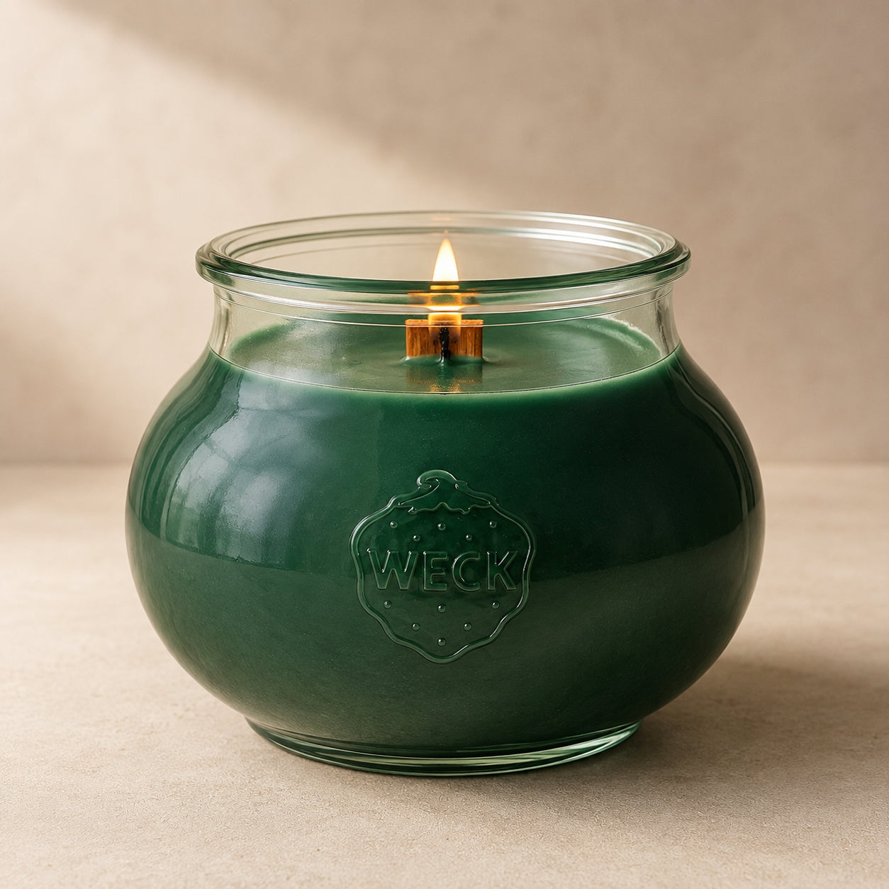 Grüne Grande Duftkerze mit 140 Std. Brenndauer aus Pflanzenwachs im bauchigen, eleganten WECK-Glas von CandleDeko, brennend vor neutralem Hintergrund.