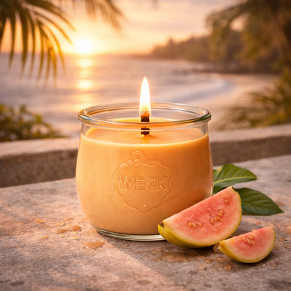 Große brennende CandleDeko Guave Colada Duftkerze im WECK-Glas am Strand neben frischen Guaven-Spalten