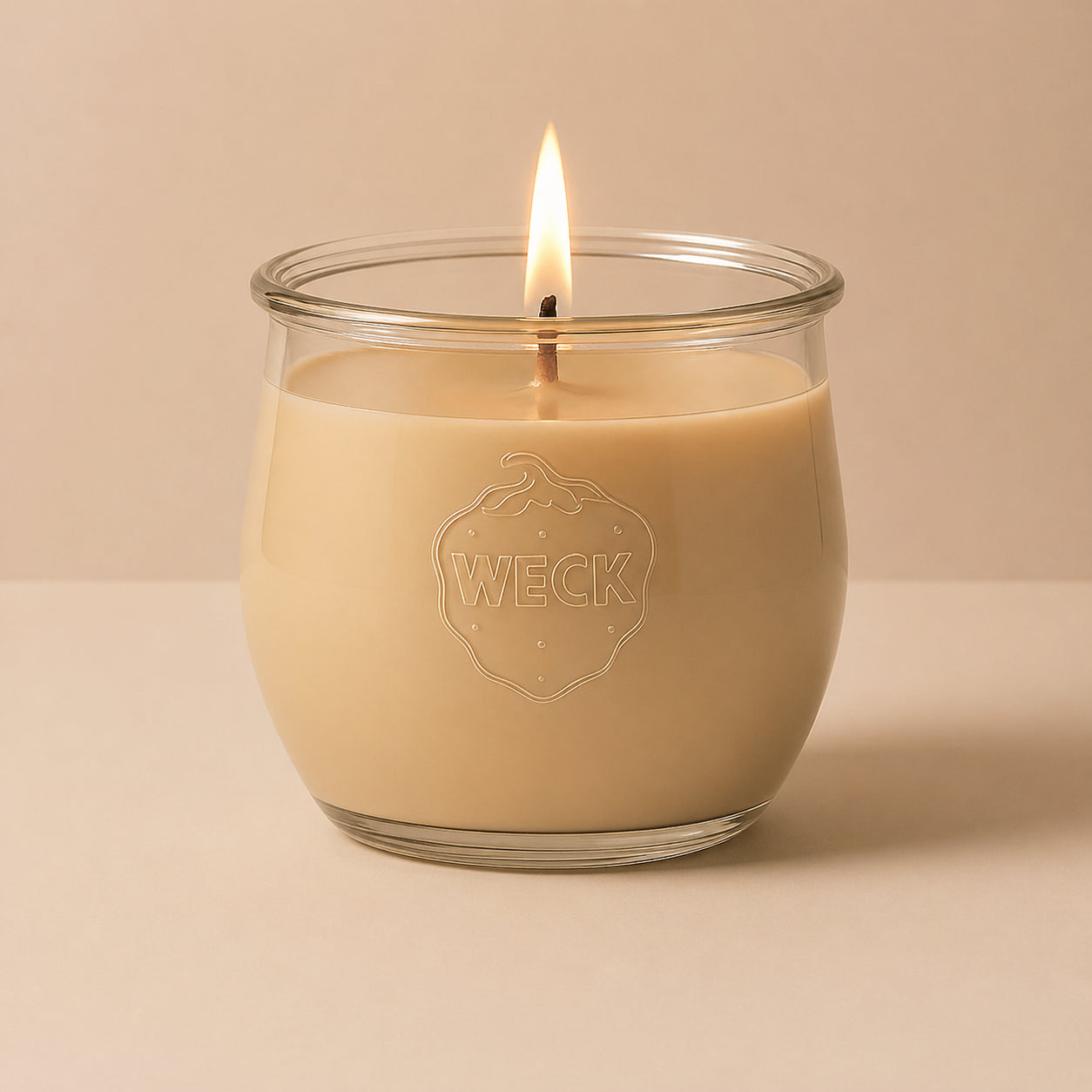 Brennende beige CandleDeko grosse Duftkerze im WECK-Tulpenglas vor neutralem Hintergrund.