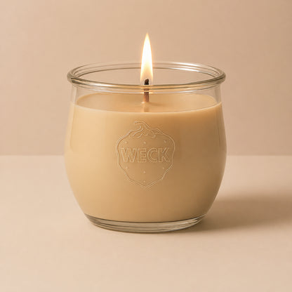 Brennende beige CandleDeko grosse Duftkerze im WECK-Tulpenglas vor neutralem Hintergrund.