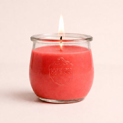 Brennende rosa CandleDeko grosse Duftkerze im WECK-Tulpenglas vor neutralem Hintergrund.