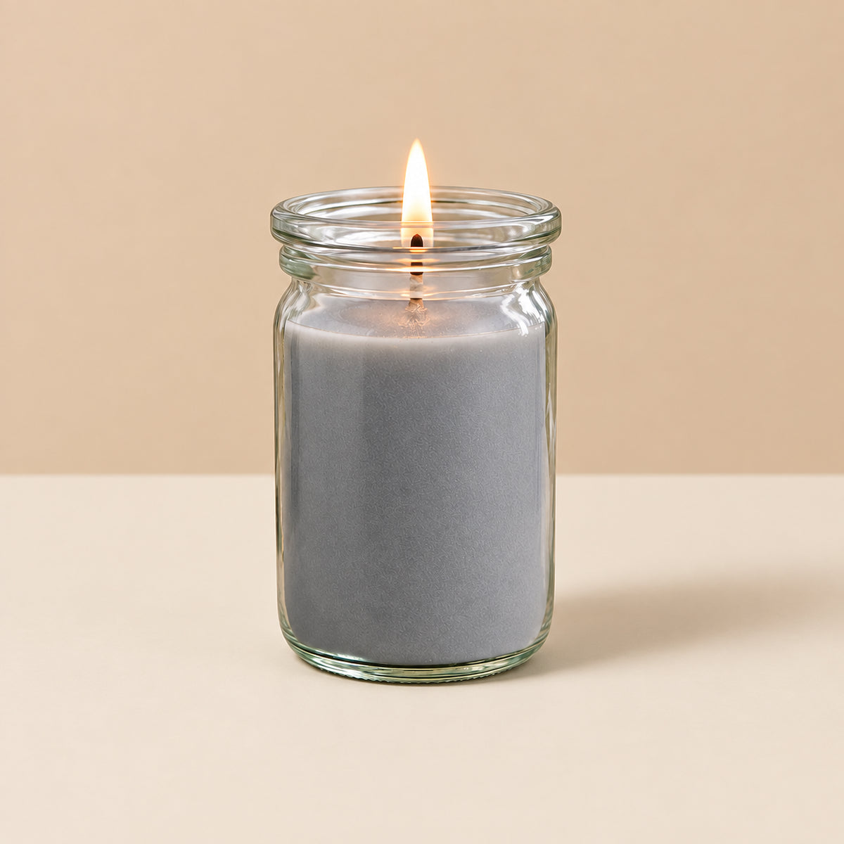 Graue kleine Duftkerze aus Kokoswachs im WECK-Tulpenglas von CandleDeko, brennend vor neutralem Hintergrund.