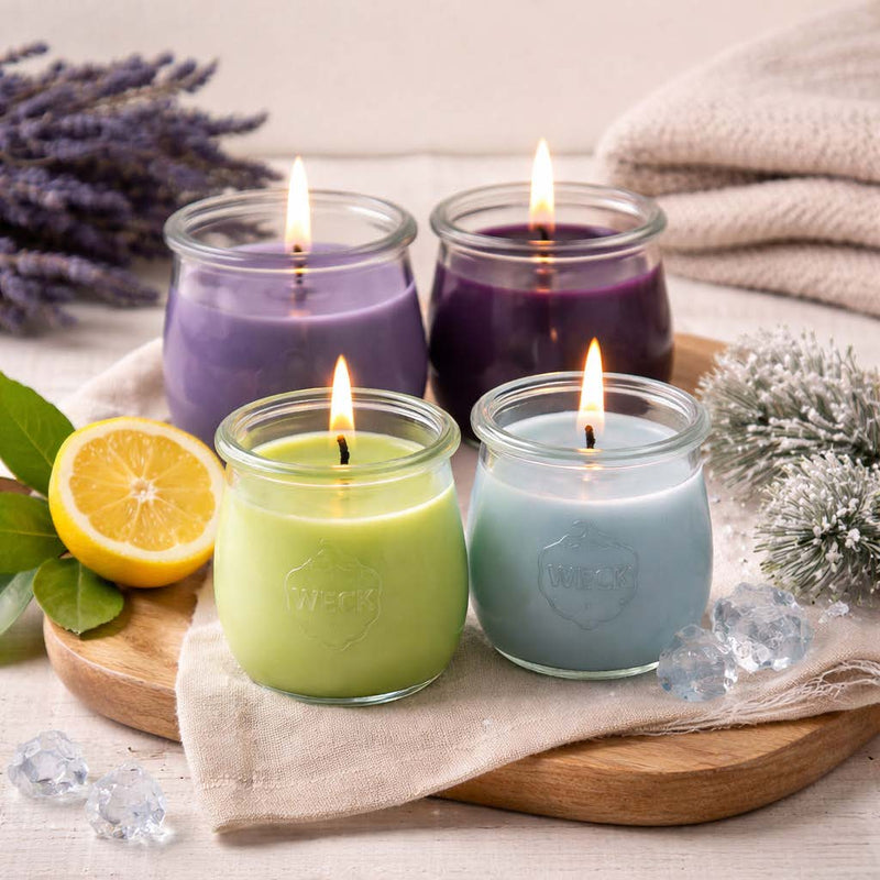 Vier brennende CandleDeko Duftkerzen aus pflanzlichem Kokoswachs im WECK-Glas als Set Zeit für mich auf einem Holzbrett neben Lavendel, Zitrone und Dekoeis.