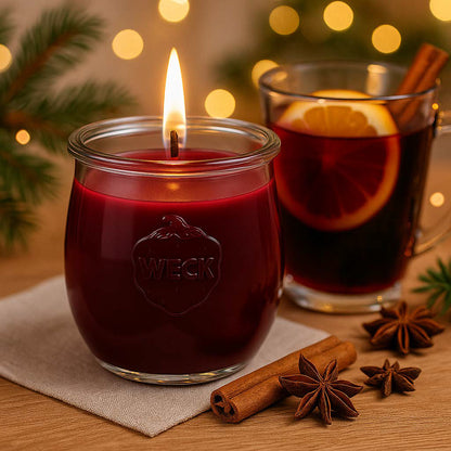 Brennende rote CandleDeko Glühwein grosse Duftkerze im WECK-Tulpenglas neben Zimtstangen und Sternanis im Lichterglanz.