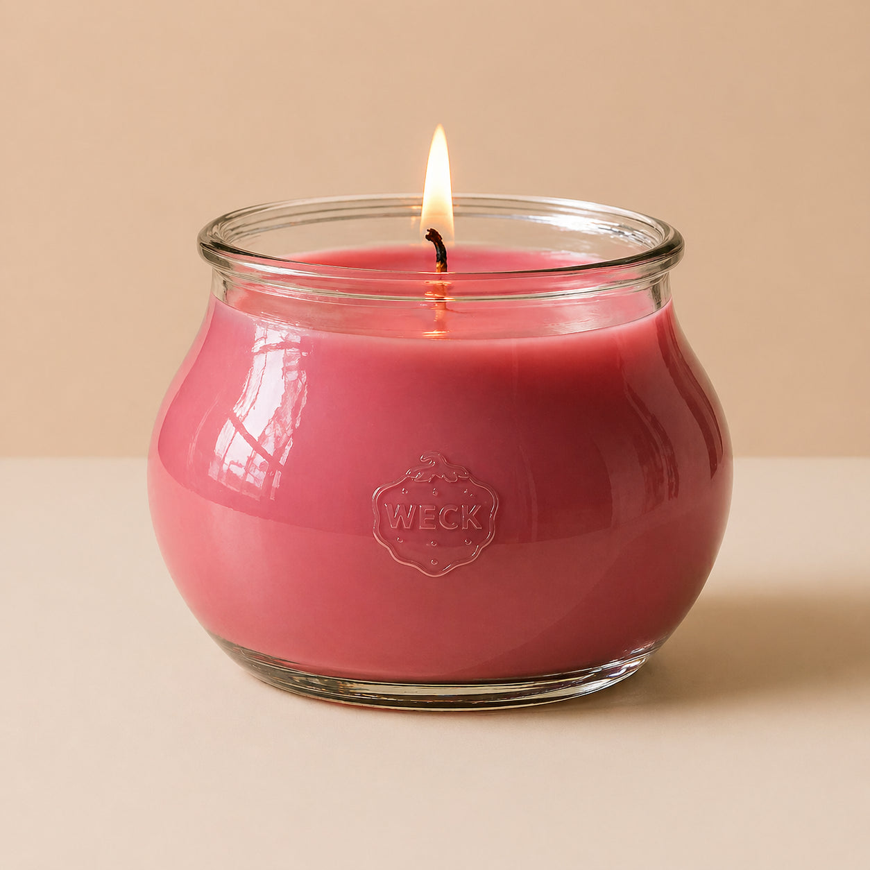 Grapefruit Duftkerze Grande aus Pflanzenwachs im WECK-Schmuckglas mit dunkelrosa Wachs und brennendem Holzdocht vor ruhigem beigem Hintergrund.