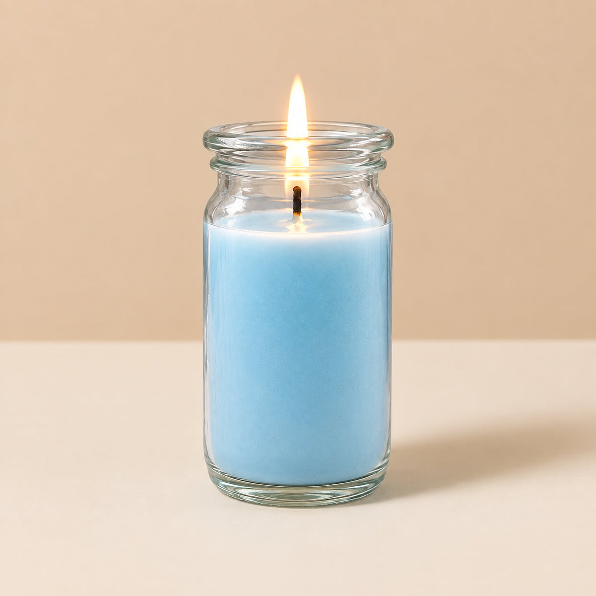 Hellblaue kleine Duftkerze aus Kokoswachs im originalen WECK-Glas von CandleDeko, brennend vor neutralem Hintergrund.