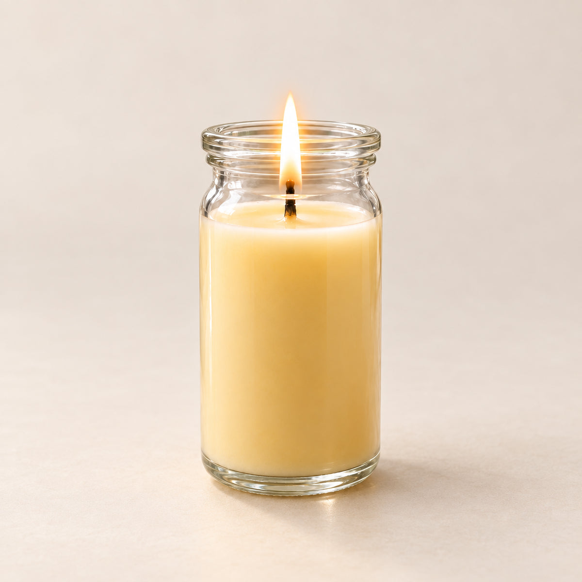 Hellgelbe kleine Duftkerze aus Kokoswachs im  WECK-Glas von CandleDeko, brennend vor neutralem Hintergrund.