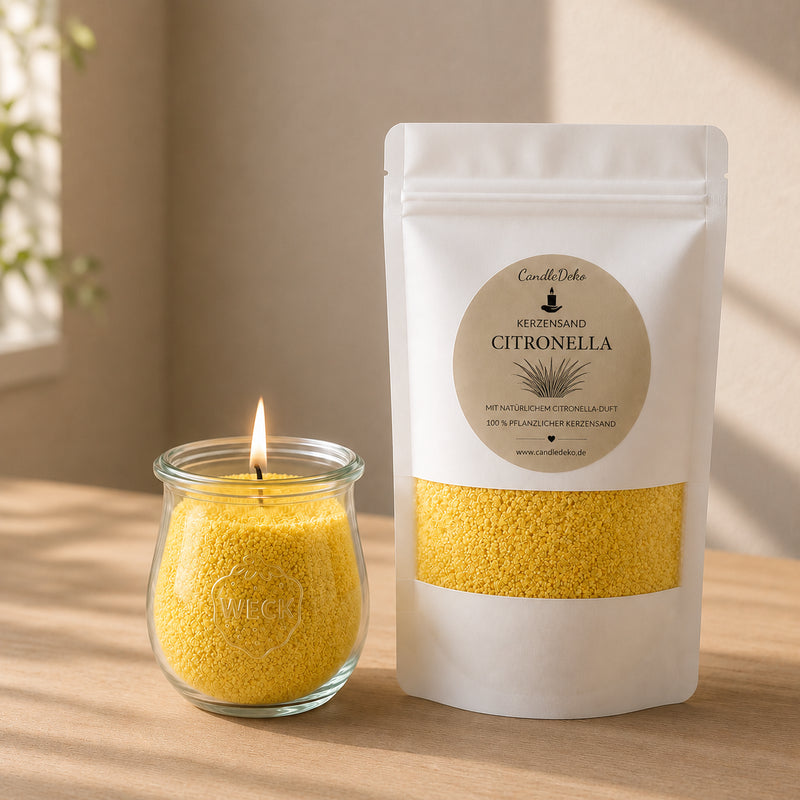 Ein weißer CandleDeko Nachfüllbeutel mit gelbem Kerzensand Citronella neben einer brennenden Kerze im bauchigen WECK-Glas auf einem hellen Holztisch.
