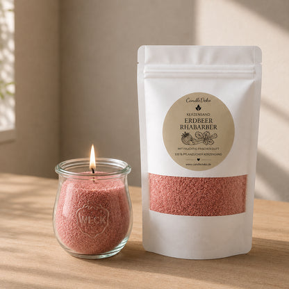 Ein weißer CandleDeko Nachfüllbeutel mit rosafarbenem Kerzensand Erdbeer Rhabarber neben einer brennenden Kerze im bauchigen WECK-Glas auf einem hellen Holztisch.