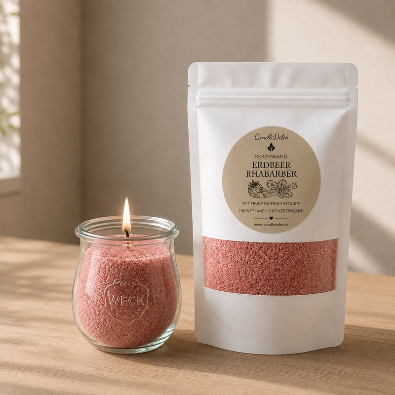 Ein weißer CandleDeko Nachfüllbeutel mit rosafarbenem Kerzensand Erdbeer Rhabarber neben einer brennenden Kerze im bauchigen WECK-Glas auf einem hellen Holztisch.