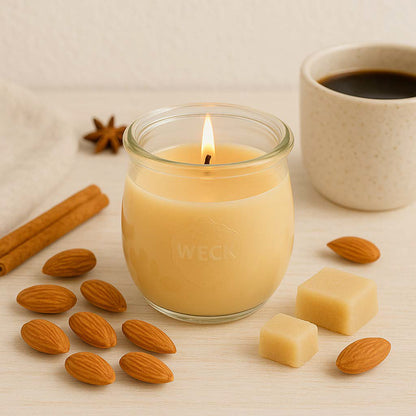 Große Marzipan und Mandel Duftkerze aus Kokoswachs im WECK-Tulpenglas neben frischem Kaffee, Marzipan und Mandeln.