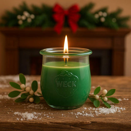 Mistelzweig große Duftkerze aus Kokoswachs im WECK-Tulpenglas von CandleDeko, auf Holztisch neben Mistelzweigen vor Kaminsims.