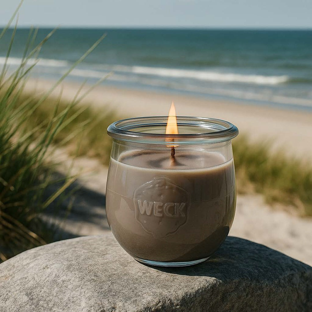 Große Nordische Küste Duftkerze aus Kokoswachs im WECK-Tulpenglas  auf Felsen vor Strand und Meer.