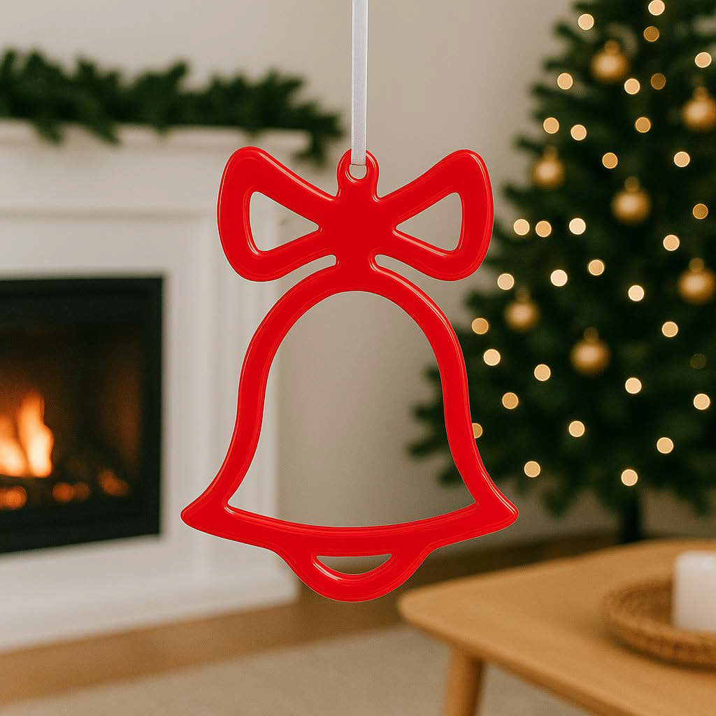 Rote handgemachte Epoxidharz-Weihnachtsglocke vor prasselndem Kaminfeuer und leuchtendem Weihnachtsbaum.