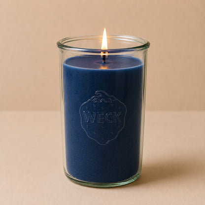 Brennende hellblaue CandleDeko XXL Duftkerze im hohen WECK-Sturzglas vor neutralem Hintergrund